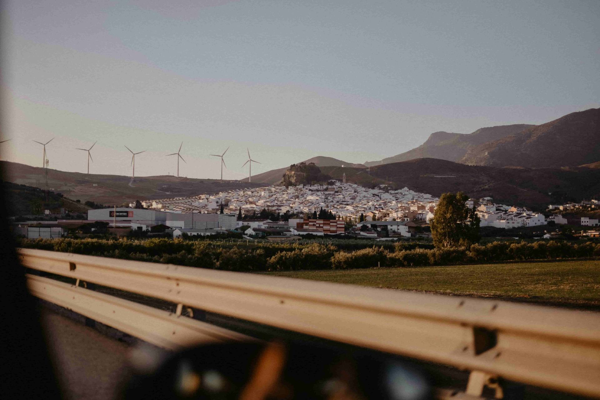 Näkymä autosta ajaessa espanjalaisen kaupungin ja tuulivoimaloiden ohi – autovakuutustarjousten vertailu